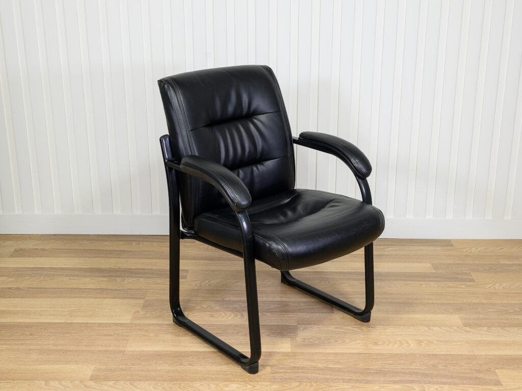 Chaise visiteur en similicuir noir avec structure en métal et des accoudoirs intégrés.