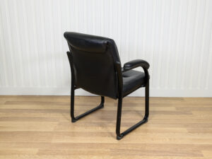 Chaise visiteur en similicuir noir avec structure en métal et des accoudoirs intégrés.