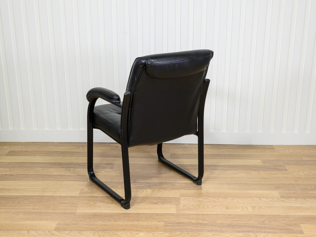 Chaise visiteur en similicuir noir avec structure en métal et des accoudoirs intégrés.