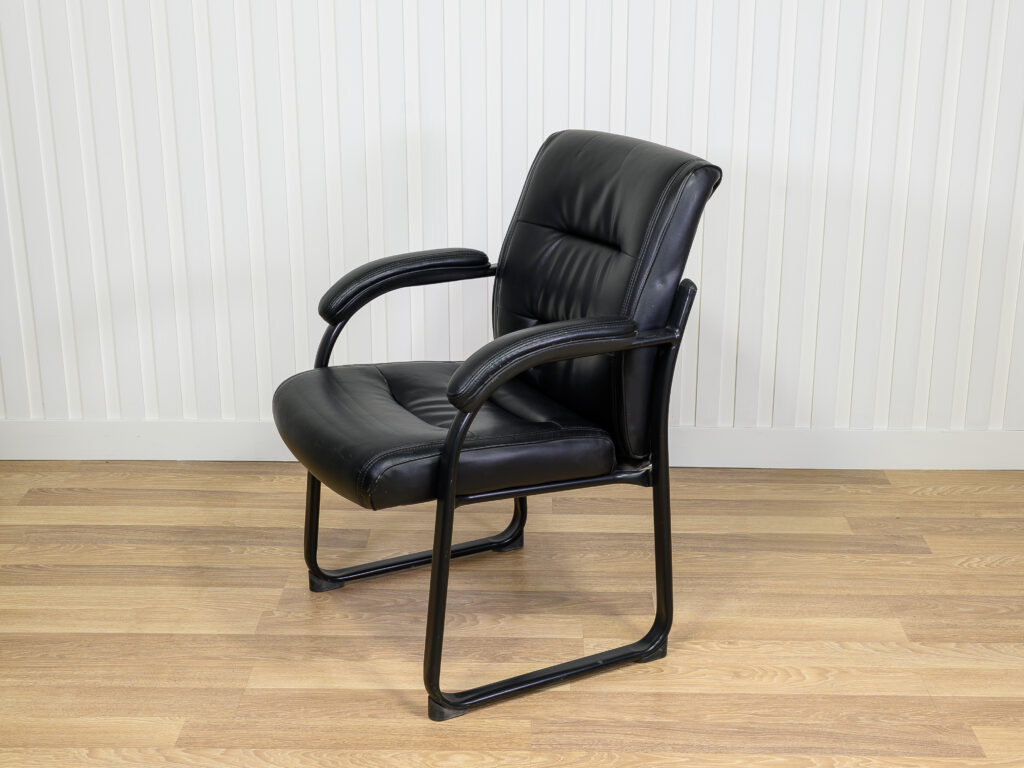 Chaise visiteur en similicuir noir avec structure en métal et des accoudoirs intégrés.