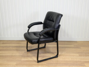 Chaise visiteur en similicuir noir avec structure en métal et des accoudoirs intégrés.